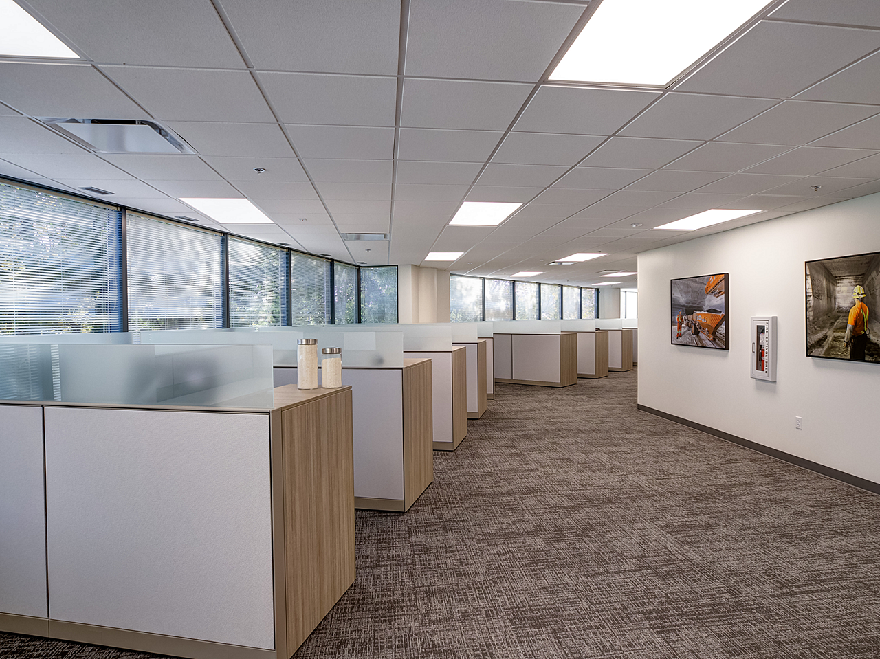 Compass Minerals Employee workstations follow window line around corridor. Light wood and white laminate facing. Salt mine artwork along walls.