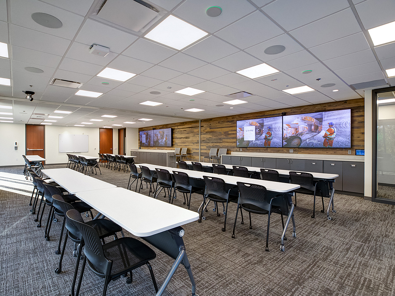 Compass Minerals Employee Training Room-white tables and black chairs, all on casters for easy moving. Wood walls and wall mounted screens with mine art.