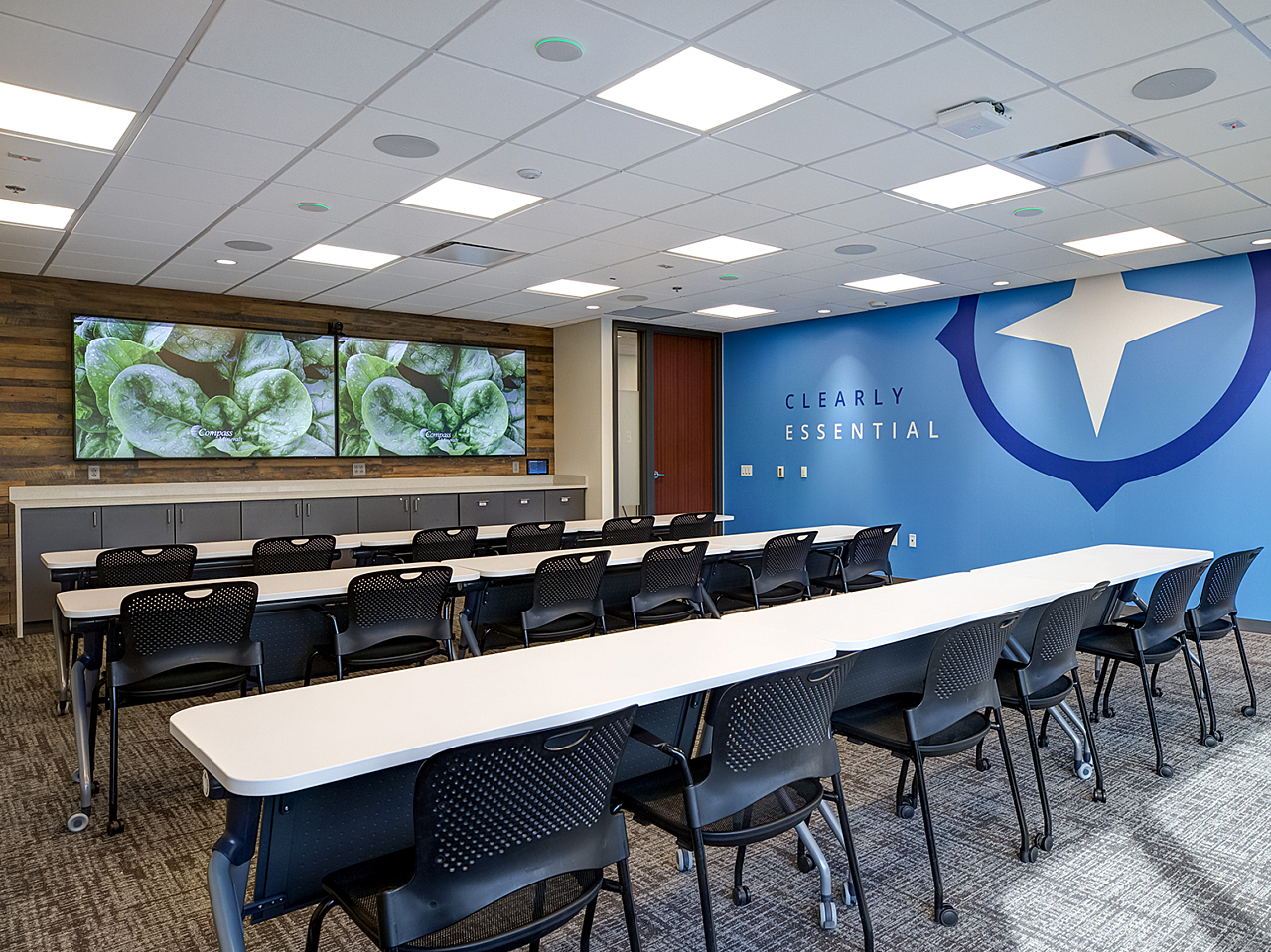 Compass Minerals Employee Training Room-white tables and black chairs, all on casters for easy moving. Wood walls and wall mounted screens with mine art.