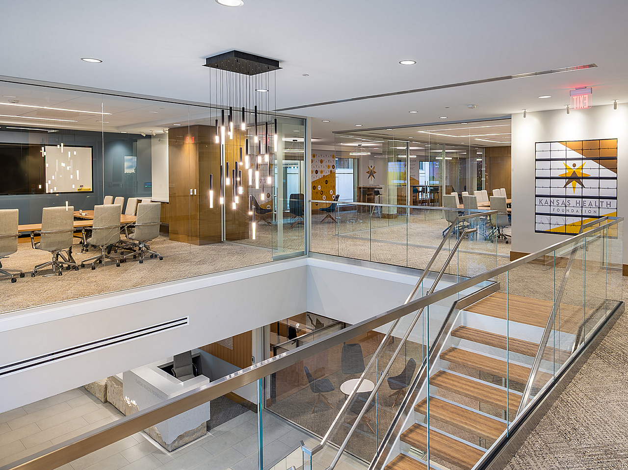 View of stair landing with a glimpse of two conference rooms and a collaborative/lounge area. You can see a reception area on the lower level.