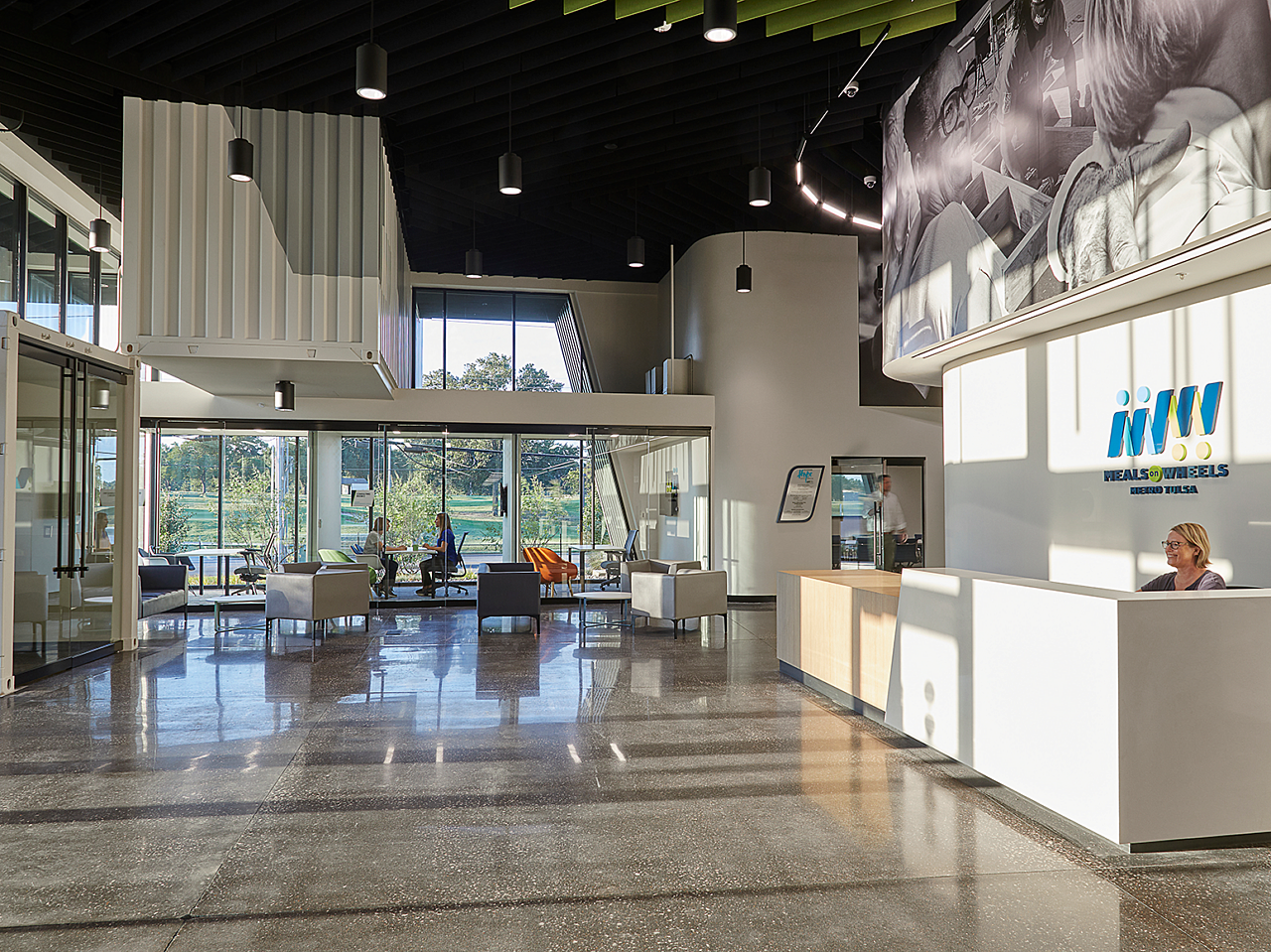 Large reception area of Tulsa's Meals on Wheels.  Reception desk on right, sitting area with tall windows and couches and chairs.