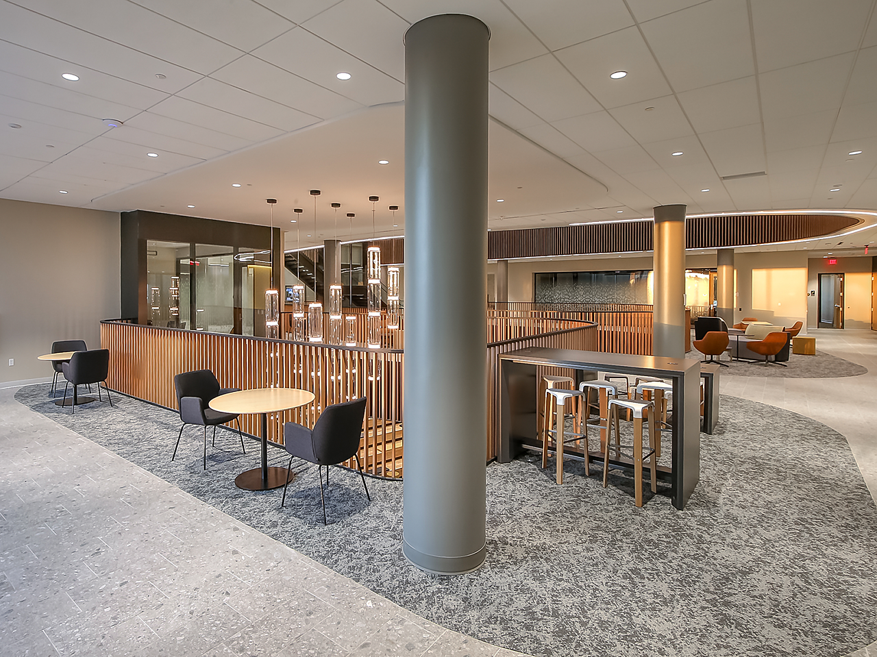 WSU's Woolsey Hall-An upper seating area with collaboration tables with stools, cafe tables with upholstered lounge seating in foreground.