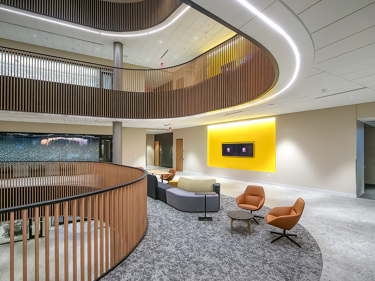 WSU's Woolsey Hall-Seating area with modular sofa with computer tables and lounge seating.  Image shows curved wooden slat railings for several floors.