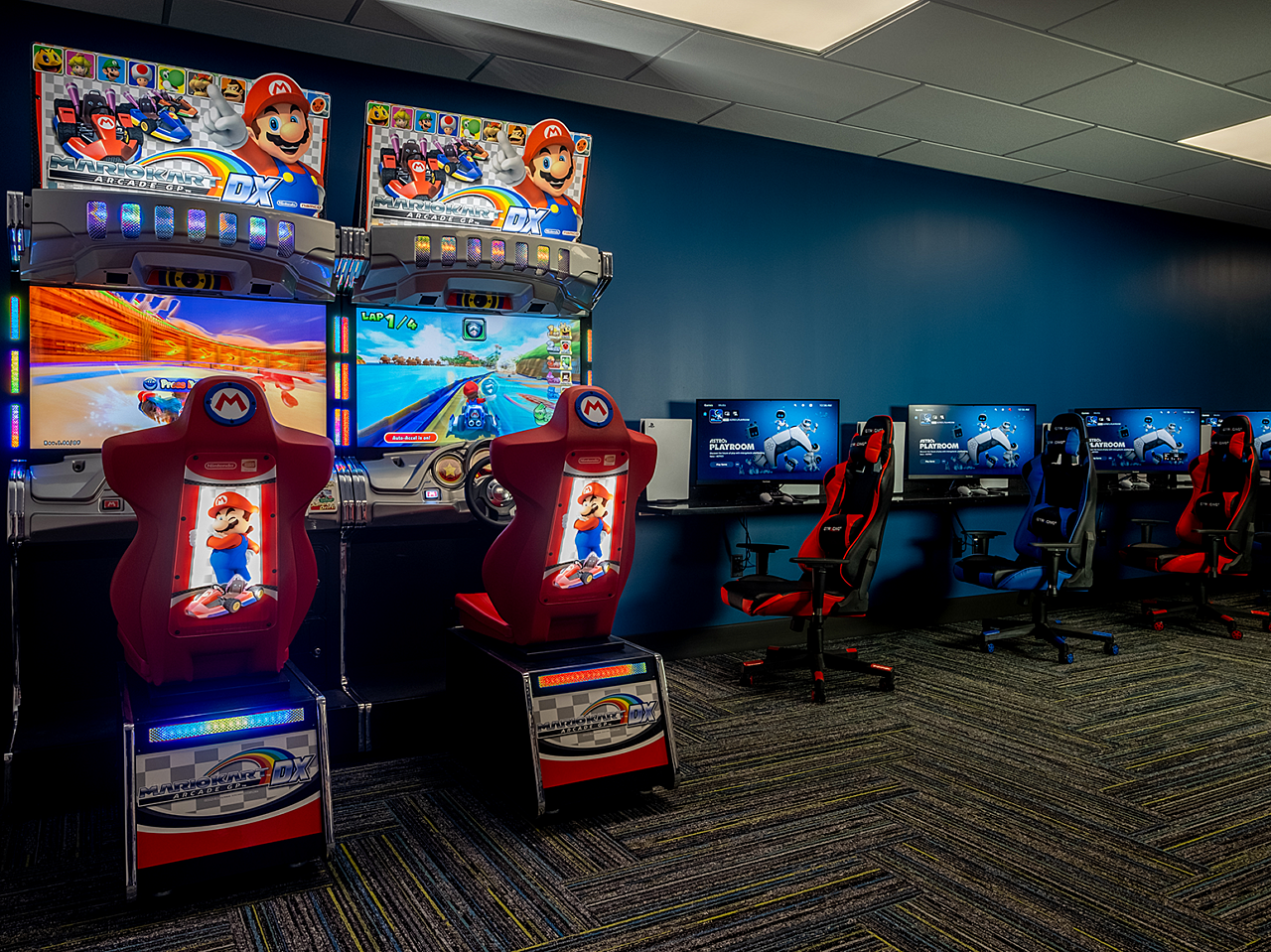 Dr. Vince Clinical Research Gaming Room with two MarioKart arcade games and several laptops and red and blue gaming chairs along a long table.