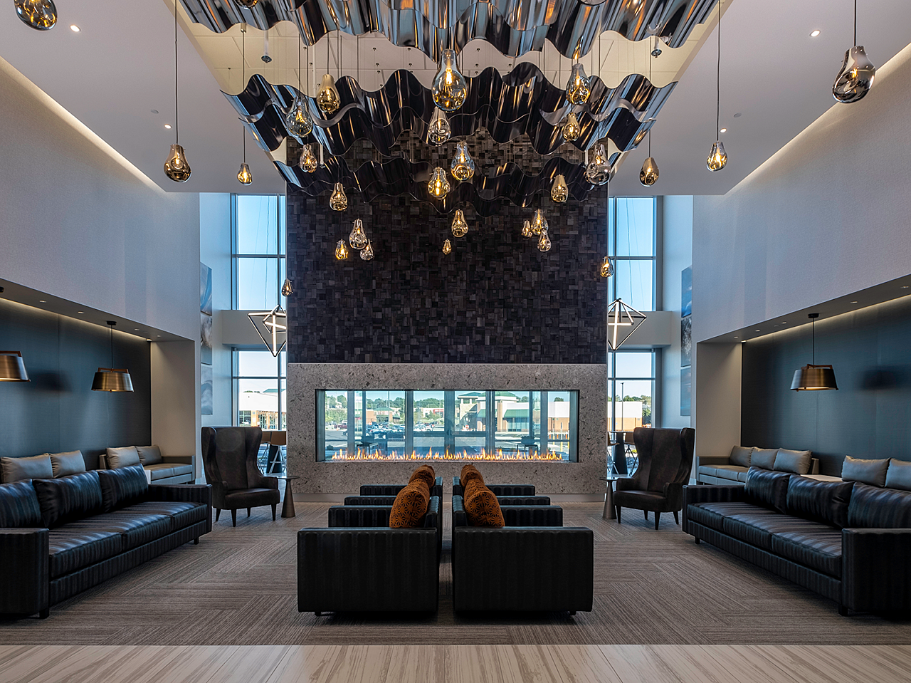 Dr. Vince Clinical Research lobby -large see-through fireplace, wavy ceiling and lighting, couches, highback chairs and banquet seating in dark neutrals