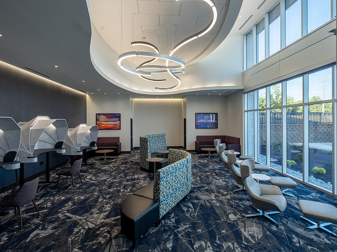 Dr. Vince Clinical Research VIP Lounge - wavy sofa down center, desk seating with domed hoods, high-back chairs along window with ottomans.
