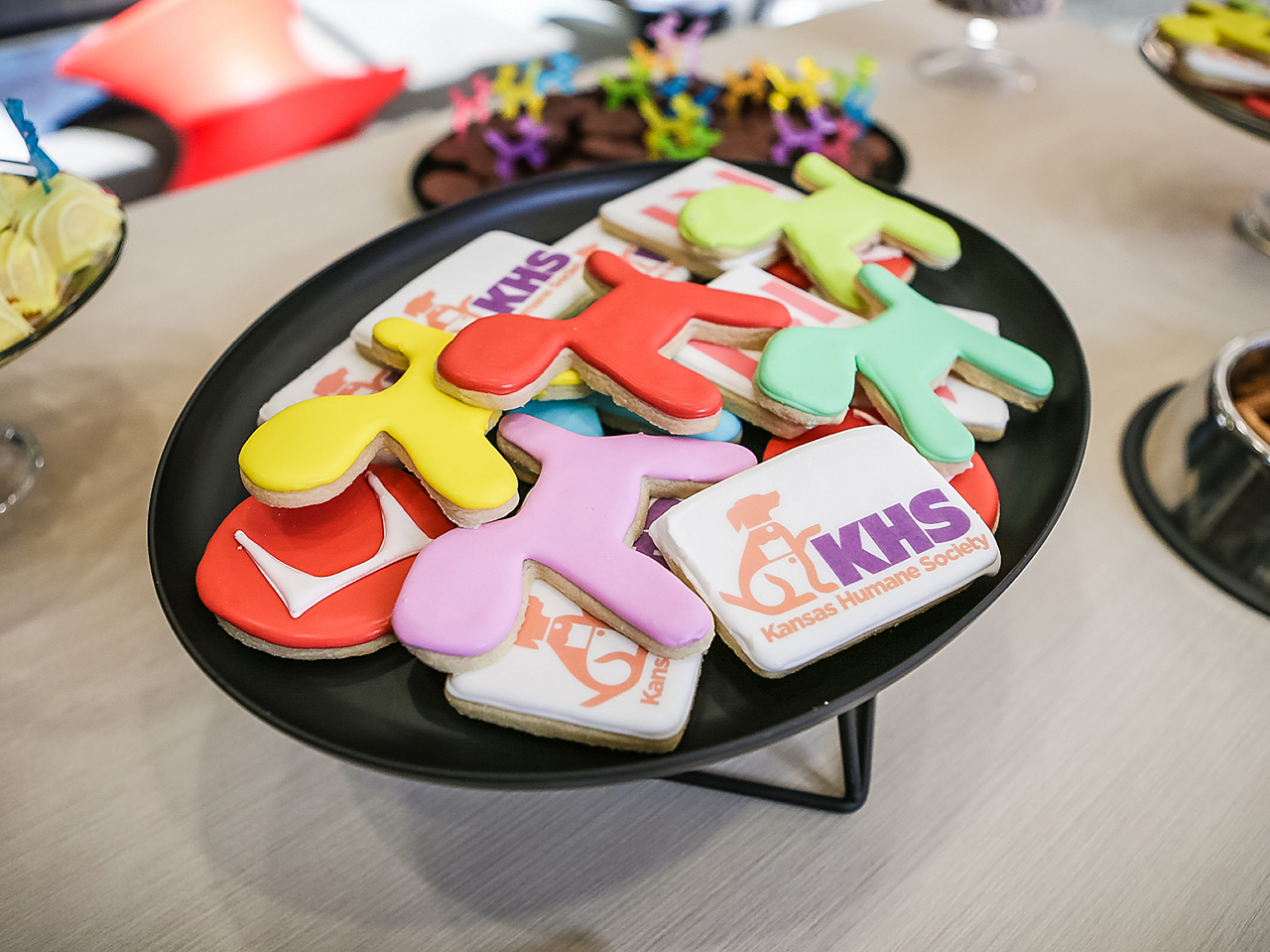 A tray of cookies shaped like Magis Puppies and with Herman Miller, John A. Marshall Co., and KS Humane Society logos