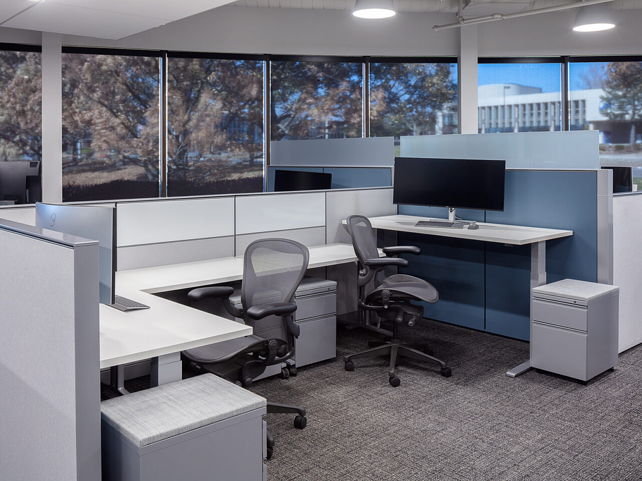 Two open-area workstations with back-to-back, height-adjustable desks and tackboard panels. Two Aeron chairs, along with ped storage units.