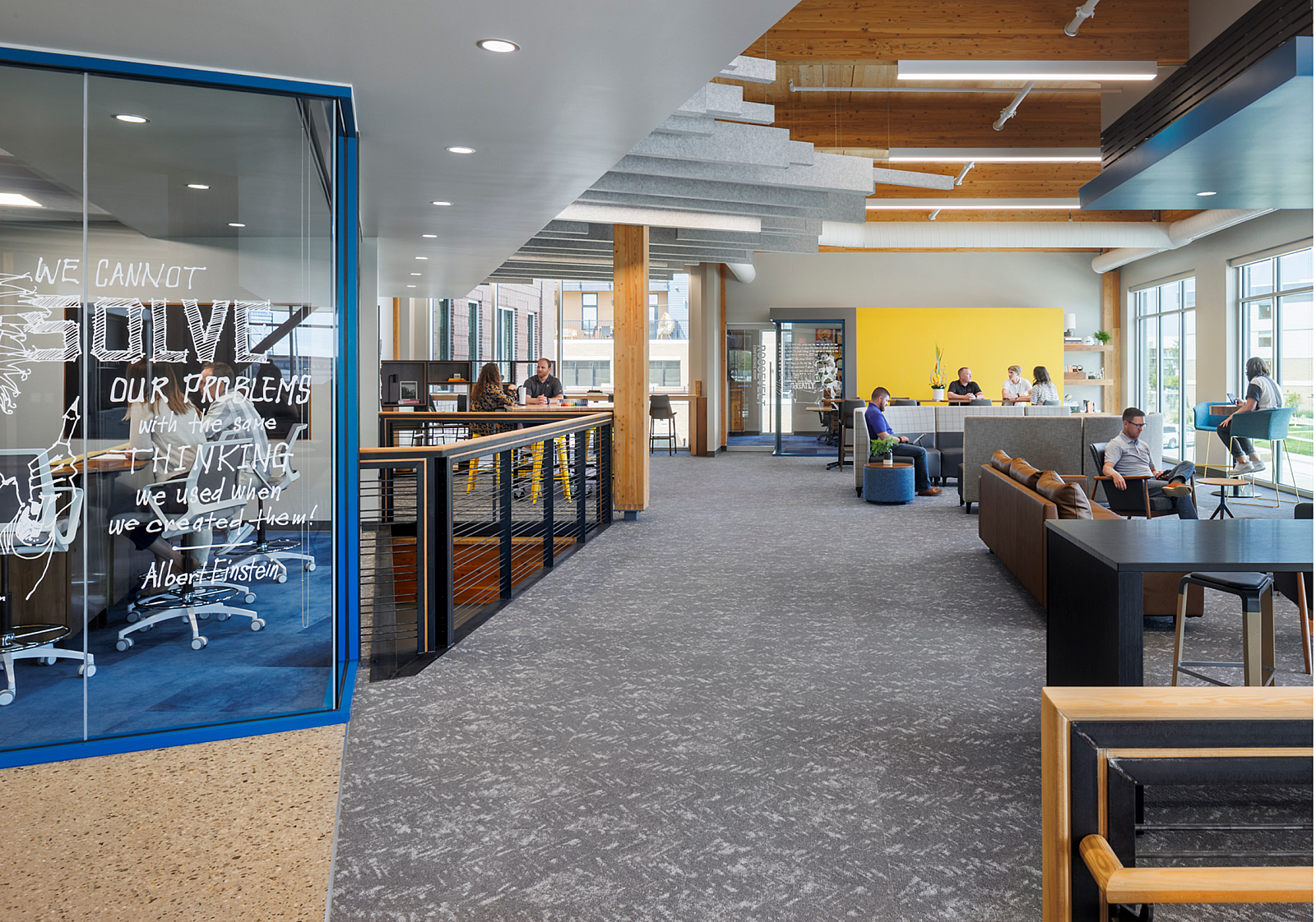 Hutton Construction open area with sofas, gathering tables with stools just off a collaborative area with Albert Einstein quote painted on the glass