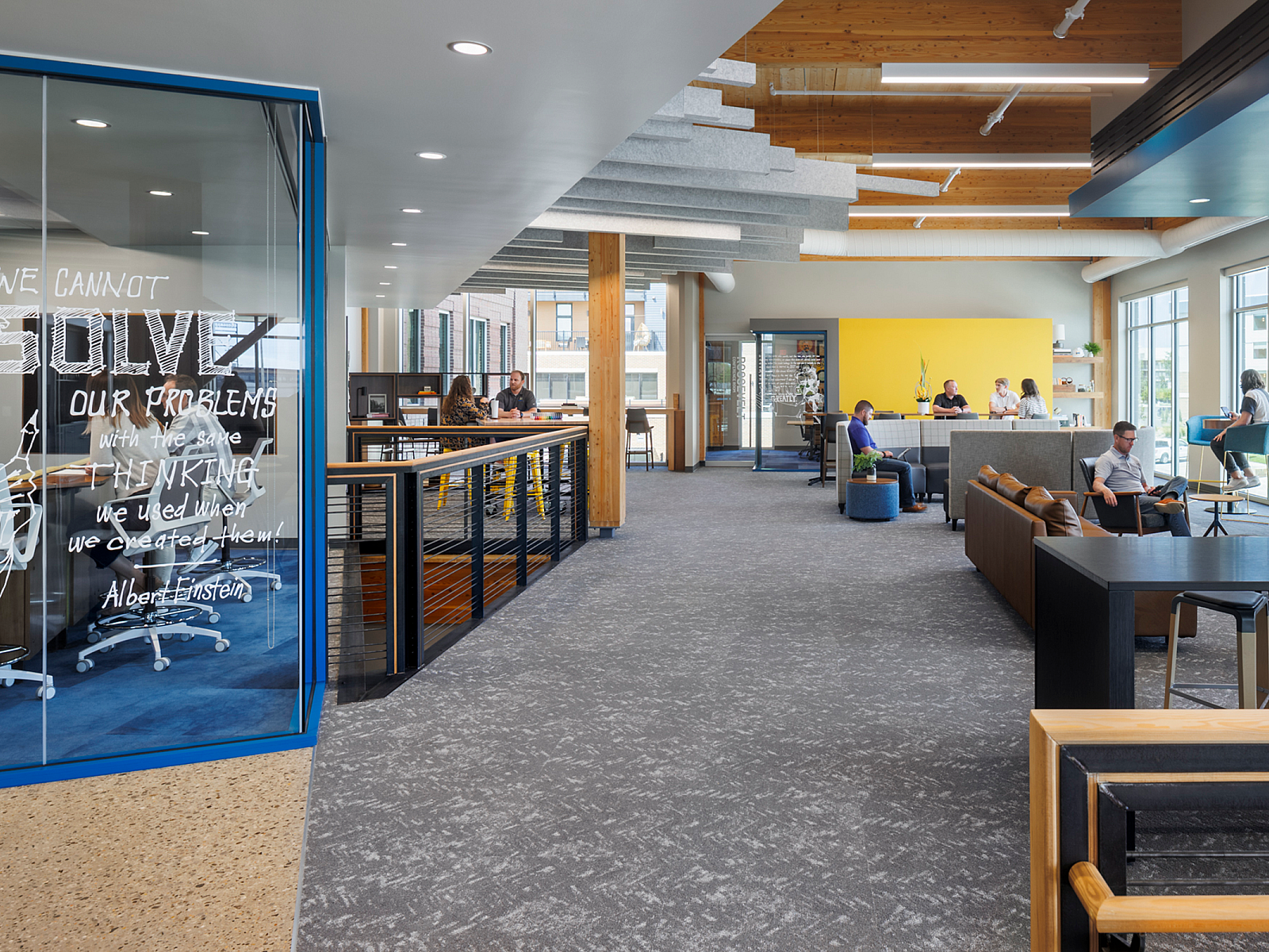Hutton Construction open area with sofas, gathering tables with stools just off a collaborative area with Albert Einstein quote painted on the glass