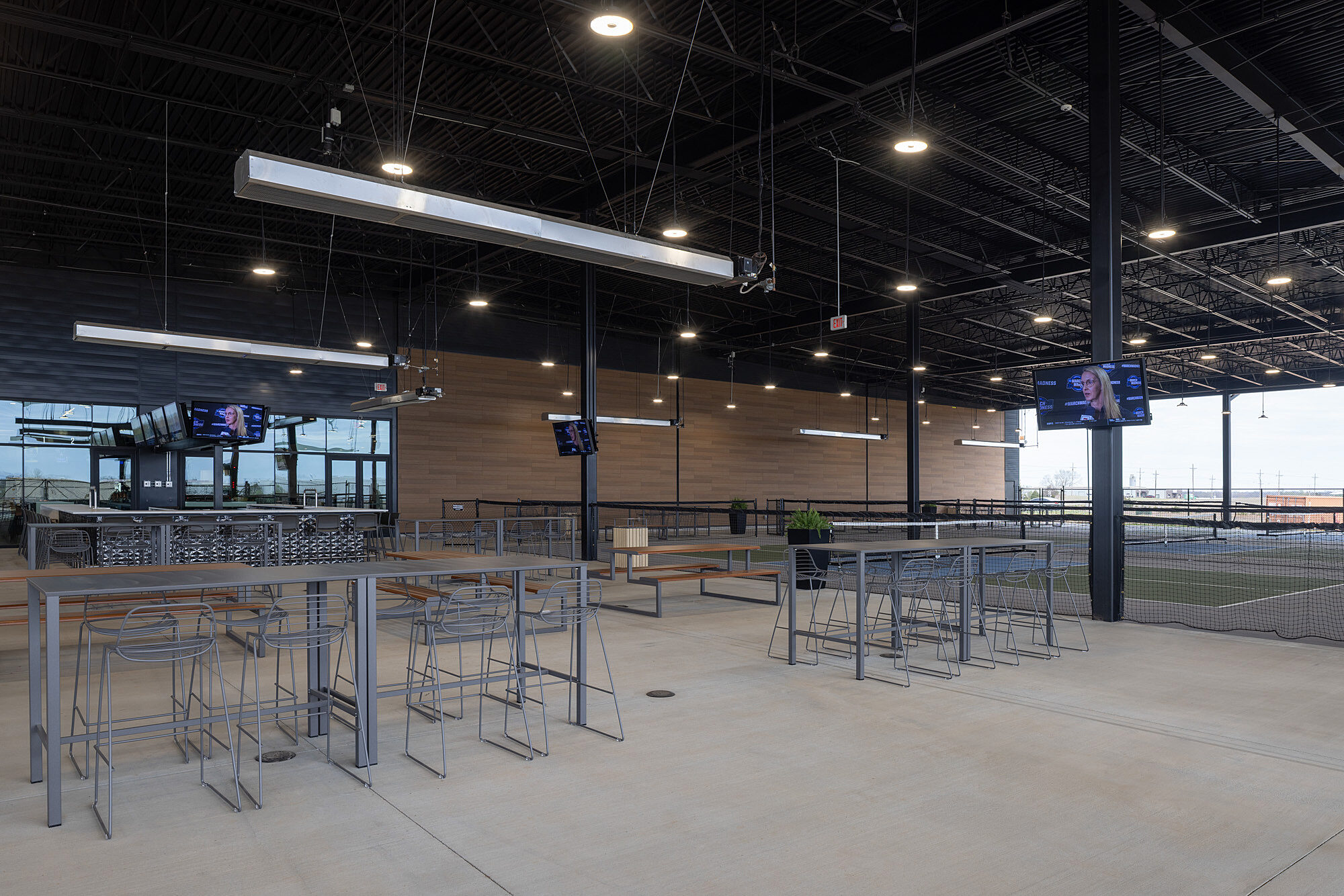 Outdoor sports bar seating area with picnic and high-top seating. Pickleball courts in the background. Part of The Hub, owned by the Tonkawa Tribe of OK.