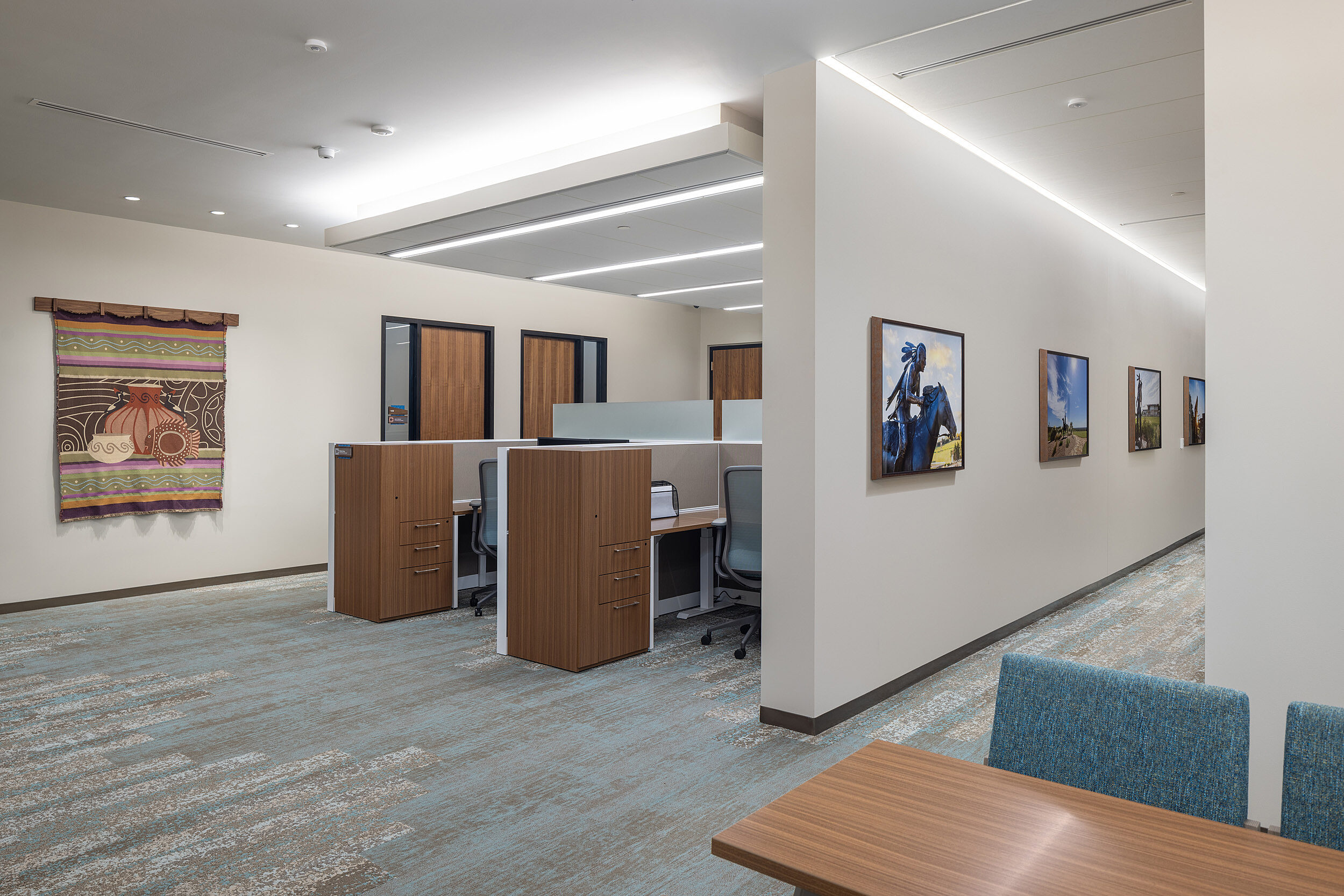 Private workstation area with built-in storage and a meeting table. Native American art line the walls in this area, as well as nearby hallway.