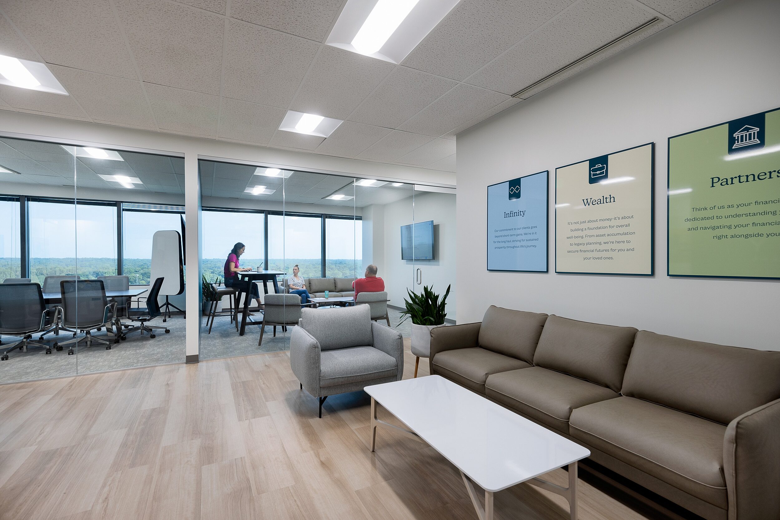 Infinity Wealth Environmental pic with lobby in foreground, conference room and collaborative room where a 3-person meeting is taking place