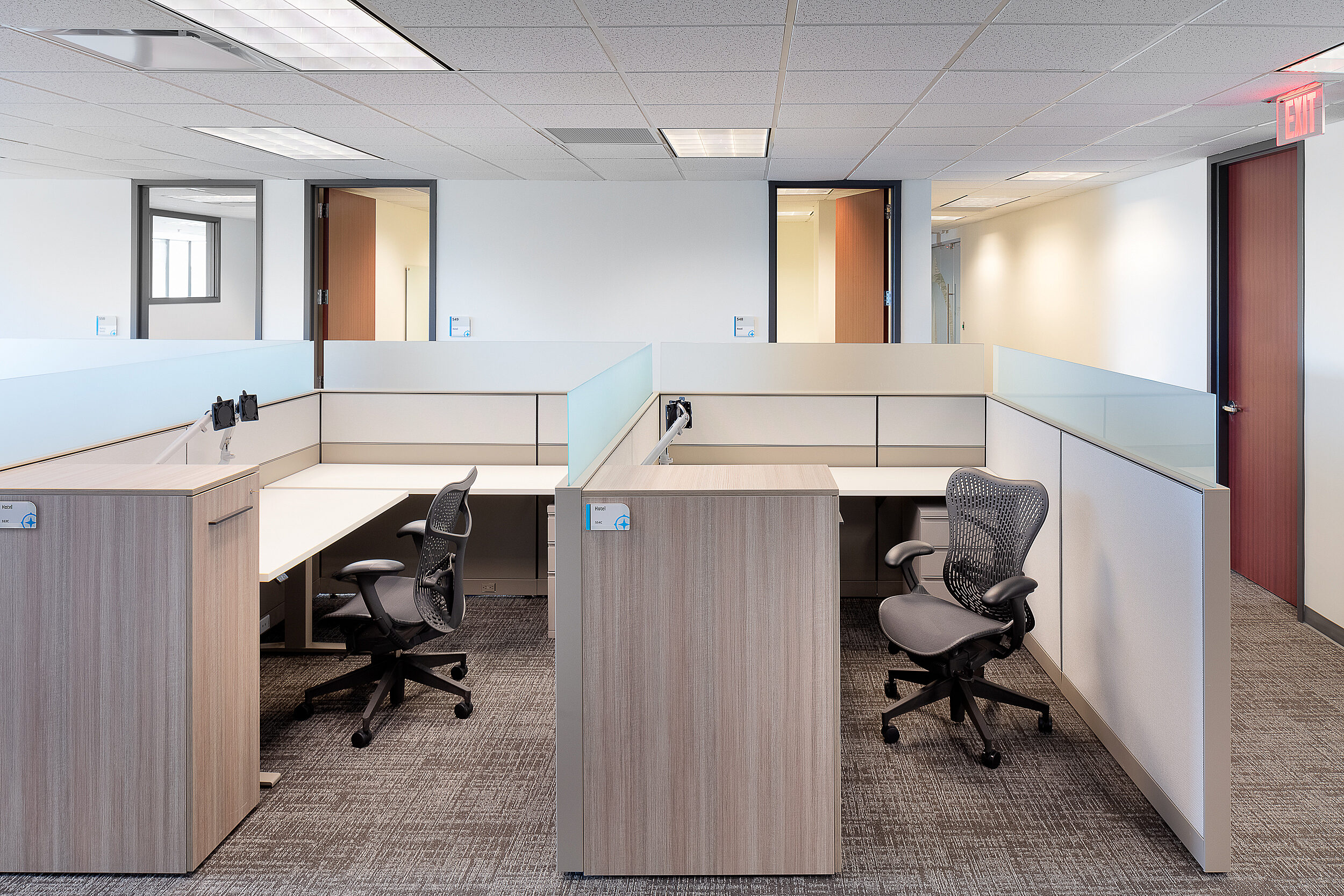 Compass Minerals "Hotel" desks for remote employees to use within office. Light colored wood and Aeron chairs. Open area desks as well as private rooms.