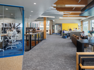Hutton Construction open area with sofas, gathering tables with stools just off a collaborative area with Albert Einstein quote painted on the glass