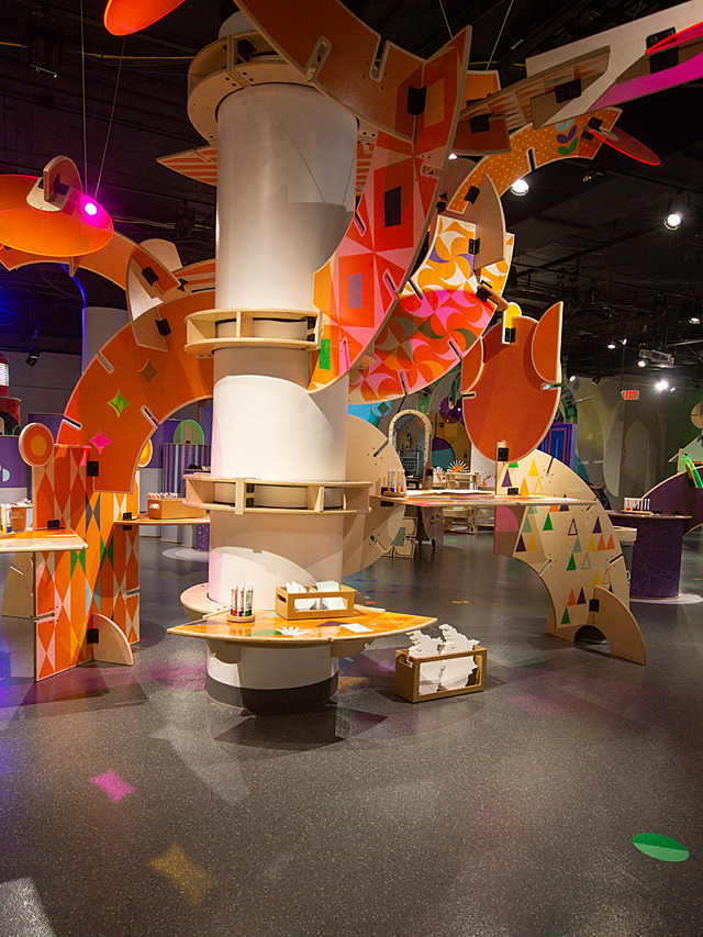 Alternate view at Hallmark Kaleidoscope art station with a tall mobile-like exhibit with orange slatted pieces flowing off of it.