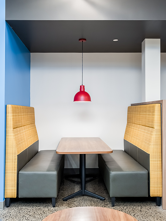 Schwan's Co nook booth with grey cushions and yellow high backs. A single red pendant light hangs from the ceiling.