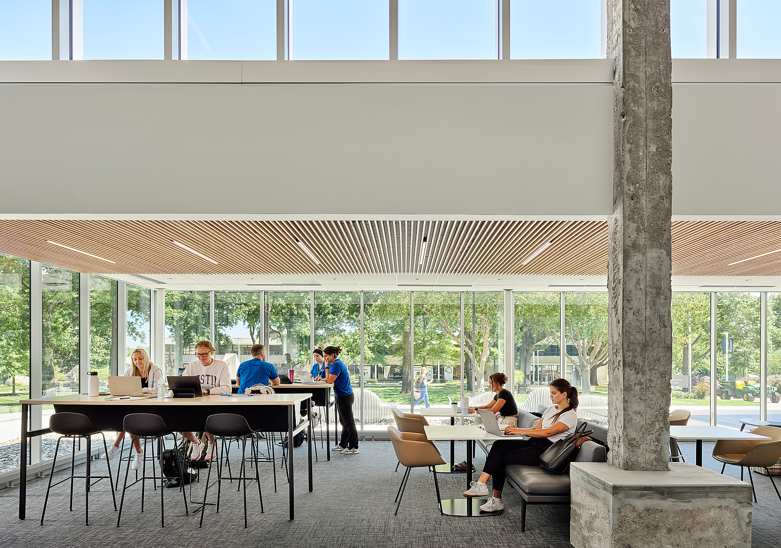 Rockhurst University open study area with a variety of high-top and bench table seating. Students on laptops work and socialize.