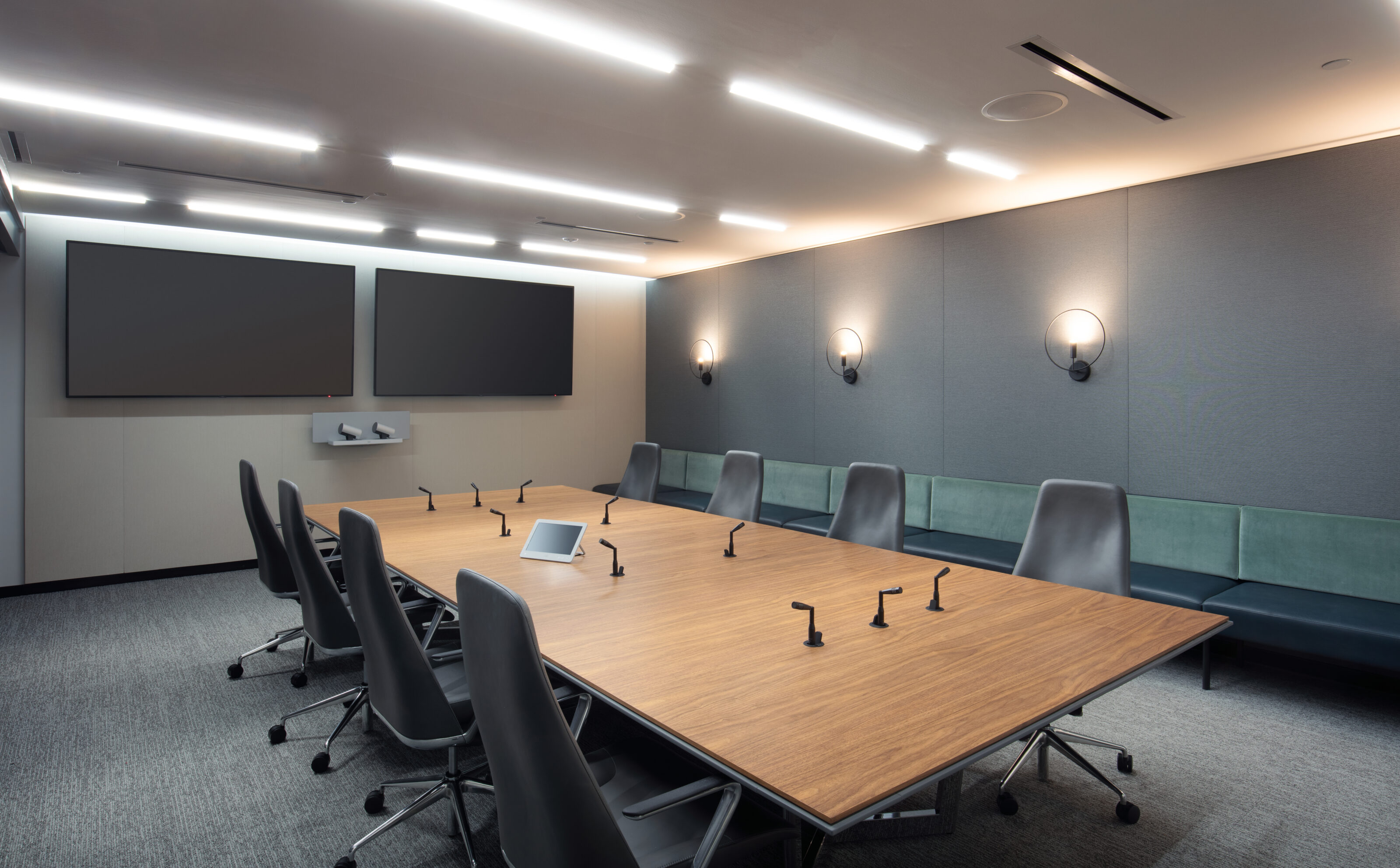 Global Reinsurance Co conference room-taper back chairs, wood laminate top table with built in speakers, two TVs and banquette seating along wall.