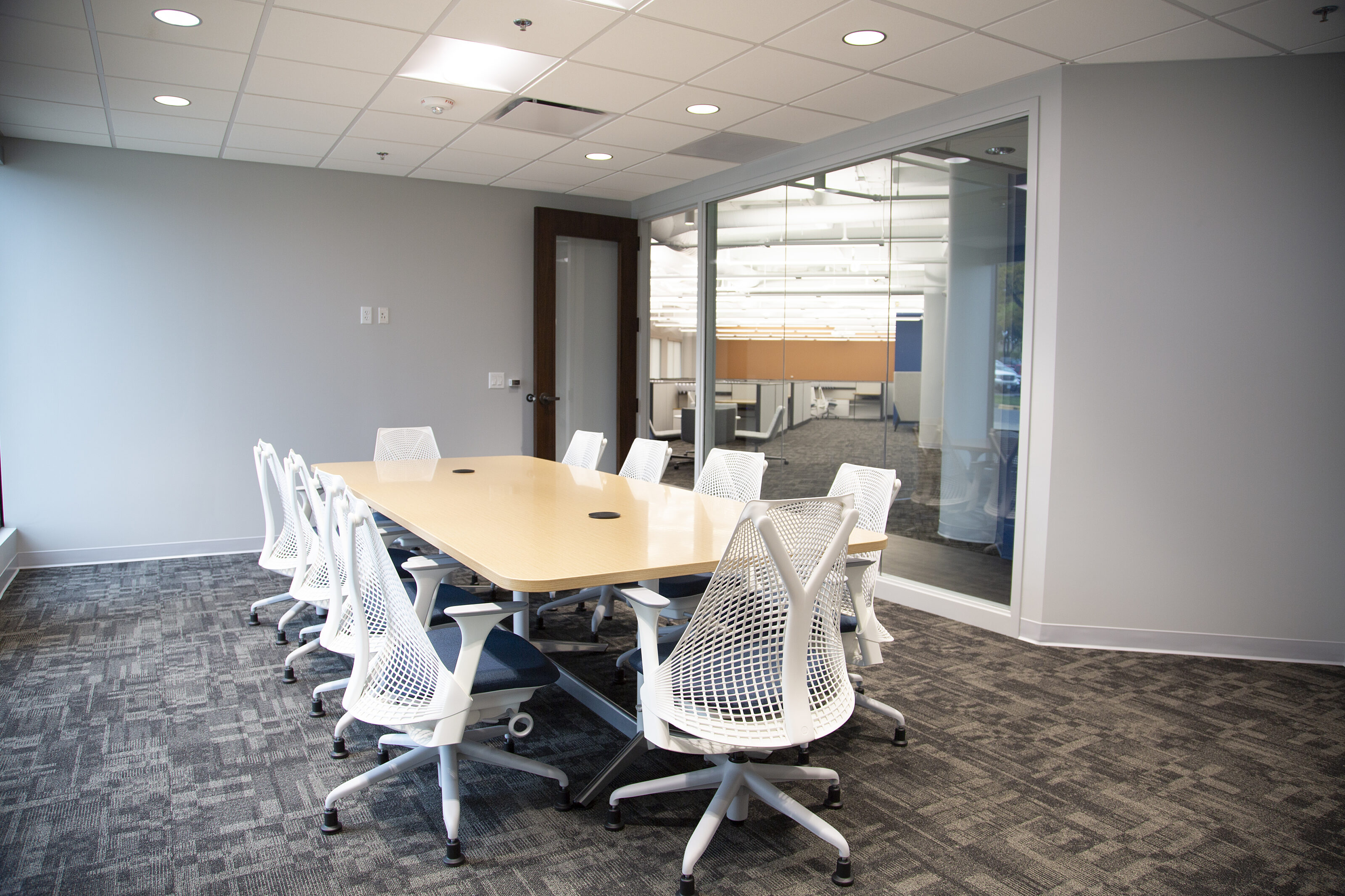 My Frieght World - Conference room with white Sayl chairs by Herman Miller. Blue seat cushions.  Glass wall looks out onto workstations.
