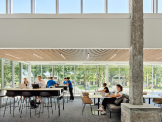 Rockhurst University open study area with a variety of high-top and bench table seating. Students on laptops work and socialize.