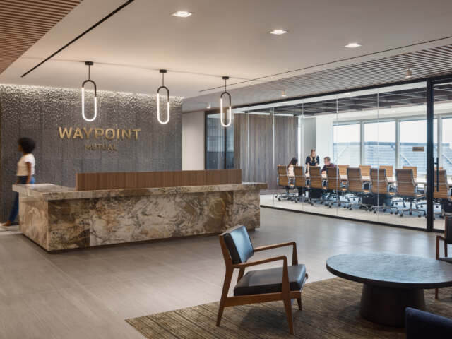 Waypoint Mutual reception area with glass-walled view of boardroom. Marbled reception desk, lounge seating area on area rug, deep browns, cream and whites.